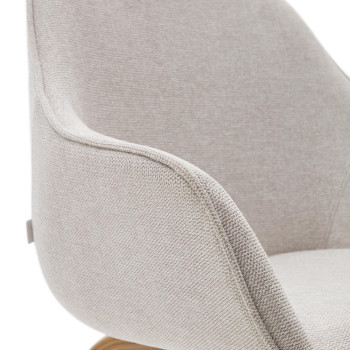 De Aleli-stoel is uitgevoerd in beige chenille met massief essenhouten poten en een natuurlijke afwerking.